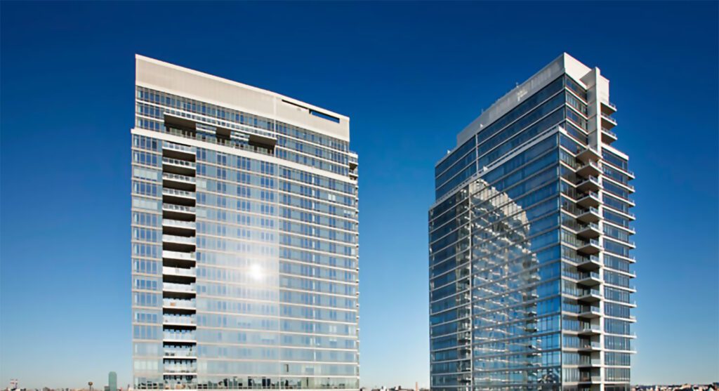 Two modern glass office buildings under a clear blue sky.