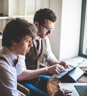 Two men working together on a tablet in a bright office.