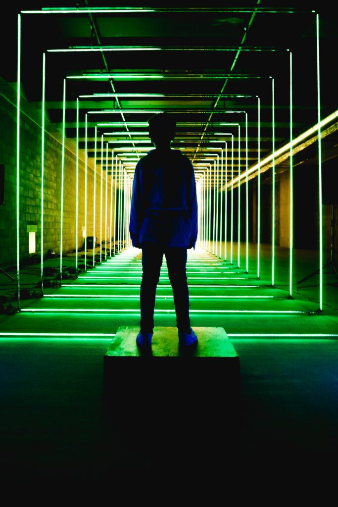 Silhouette of a person standing in a futuristic neon-lit tunnel.